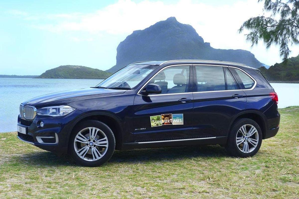 a blue car parked on the grass near the water