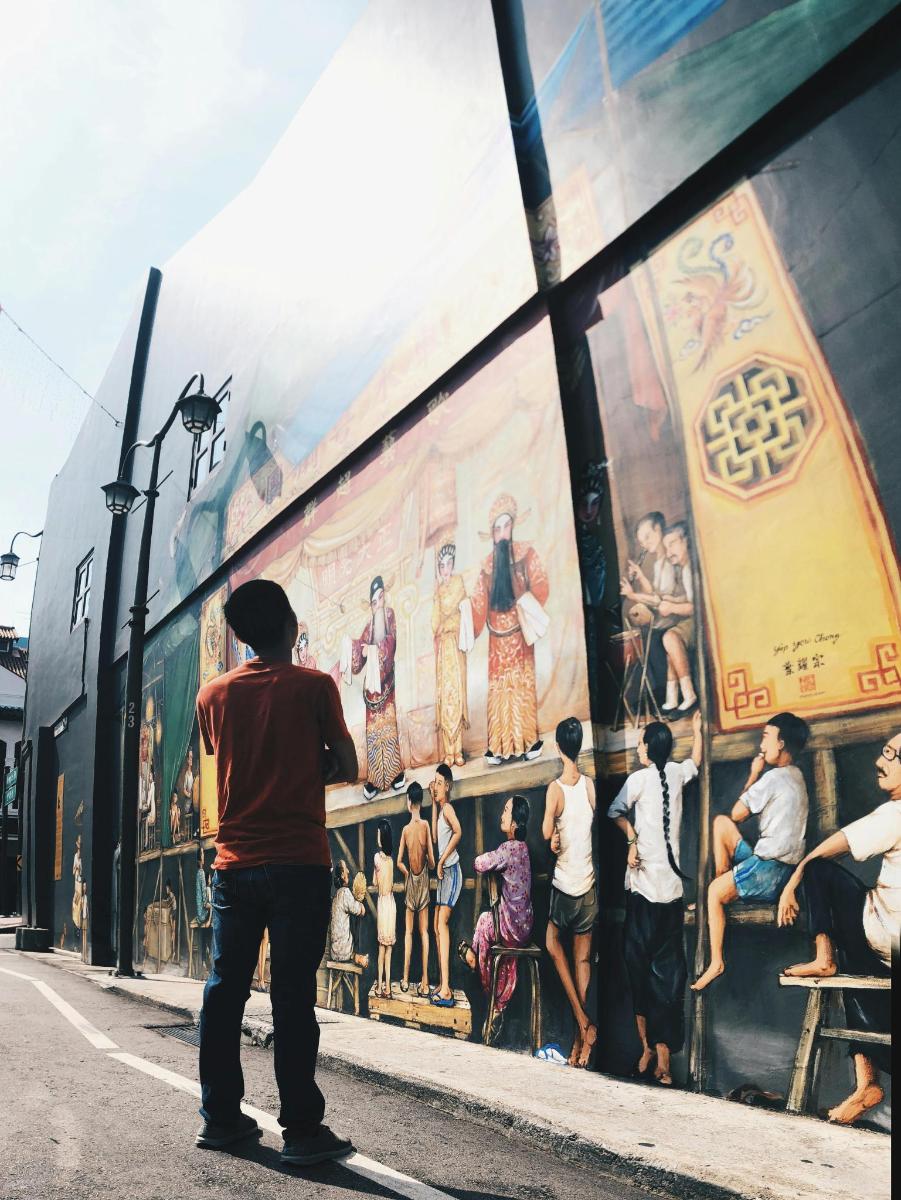 um homem em pé em frente a um mural em um prédio
