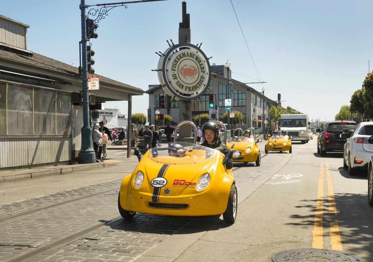 a man riding a yellow car on a city street