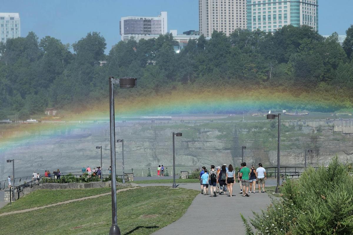 un groupe de personnes marchant devant un arc-en-ciel