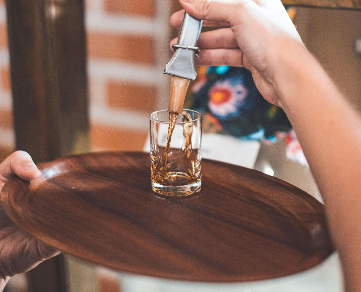 a person with a knife and a glass on a wooden plate