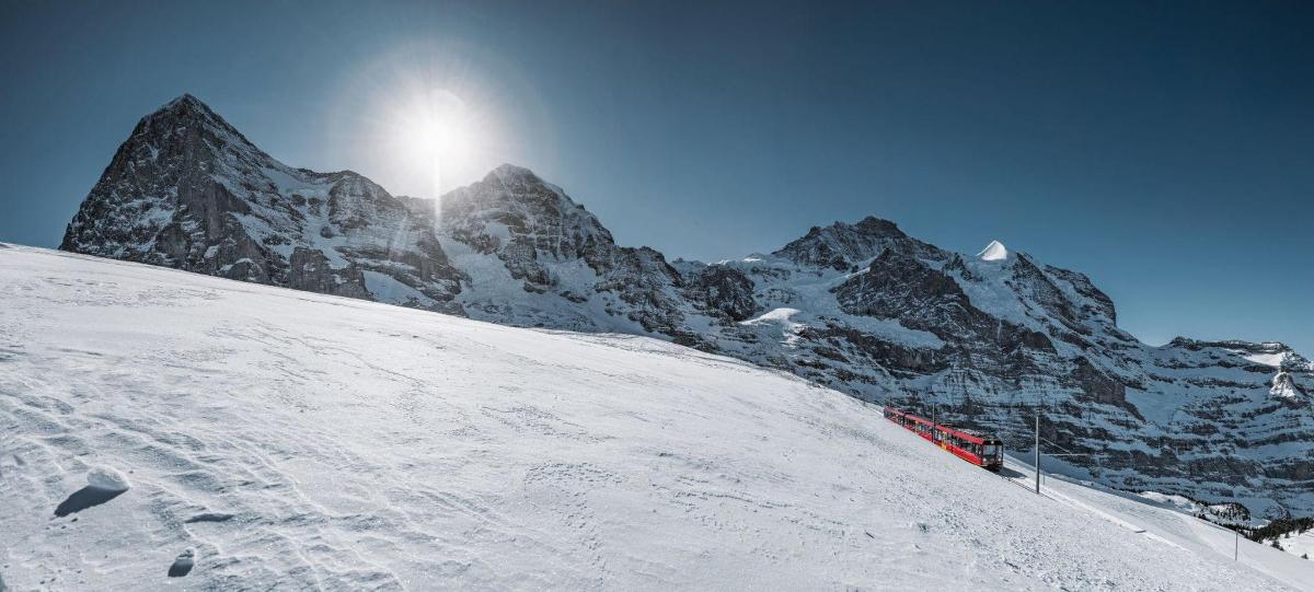 Una montaña cubierta de nieve con el sol en la cima.