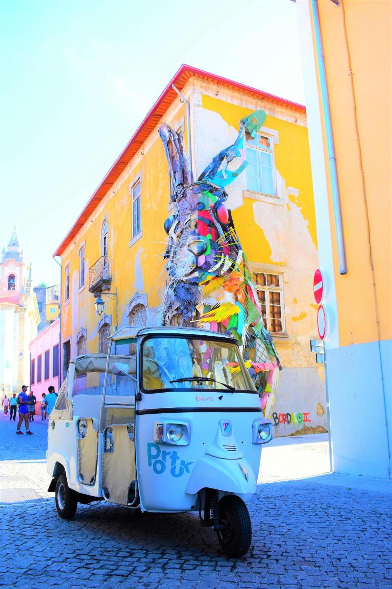 Un pequeño coche aparcado delante de un mural.