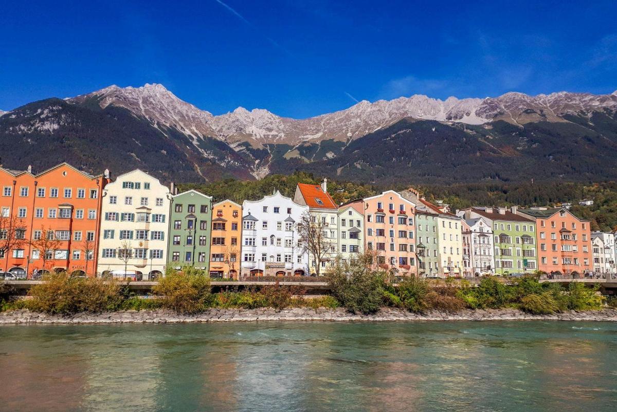 a group of buildings next to a river with mountains
