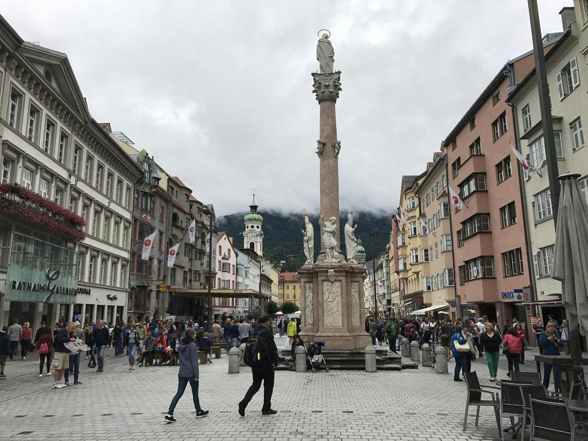 a crowd of people walking in a city with a statue