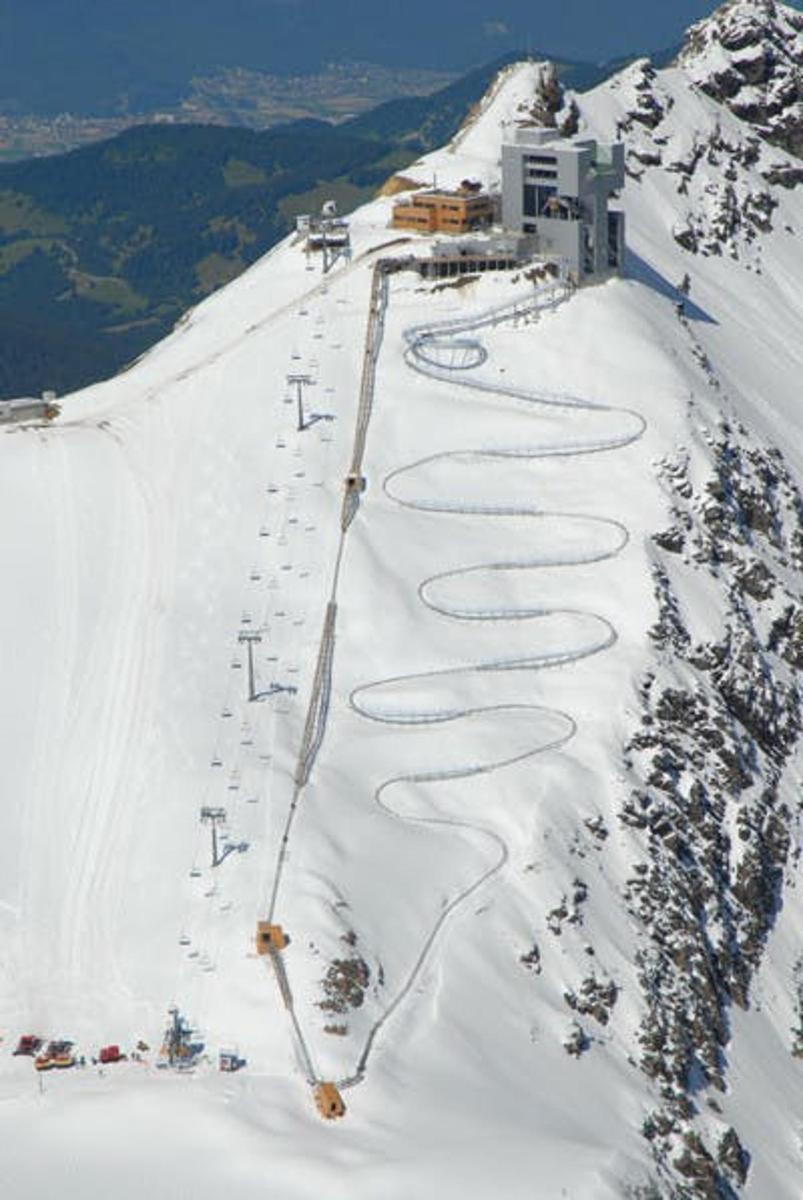 a snow covered ski slope with a building on the mountain