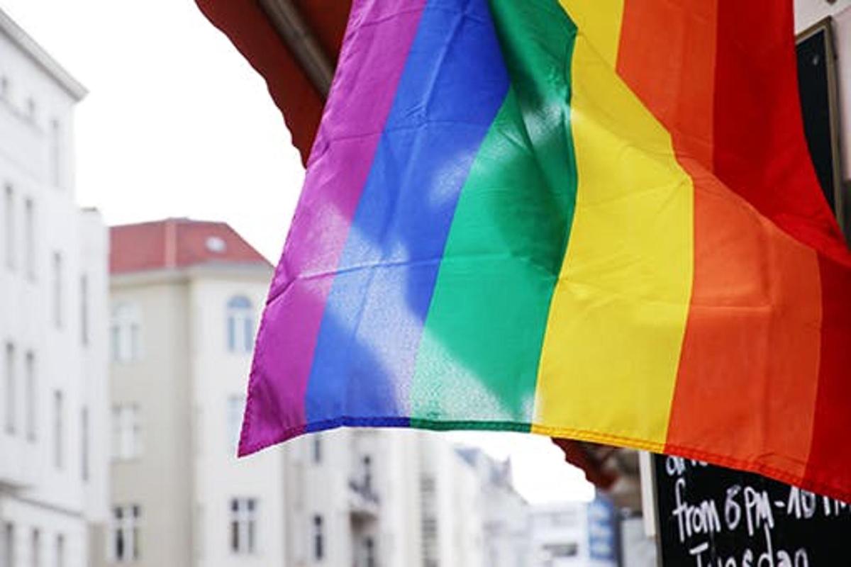 a rainbow colored flag hanging from a building