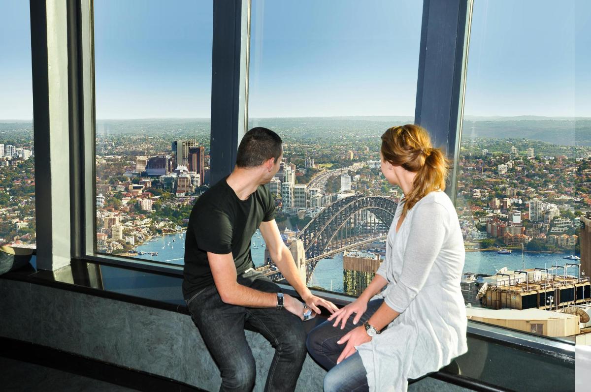 a man and a woman sitting on the edge of a skyscraper