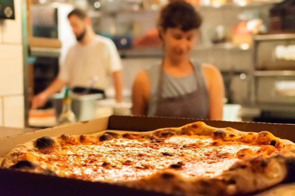 a person in a kitchen with a pizza in a box