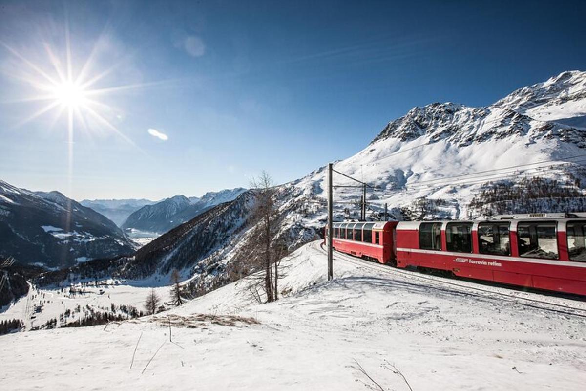 un tren vermell i blanc sobre una muntanya coberta de neu