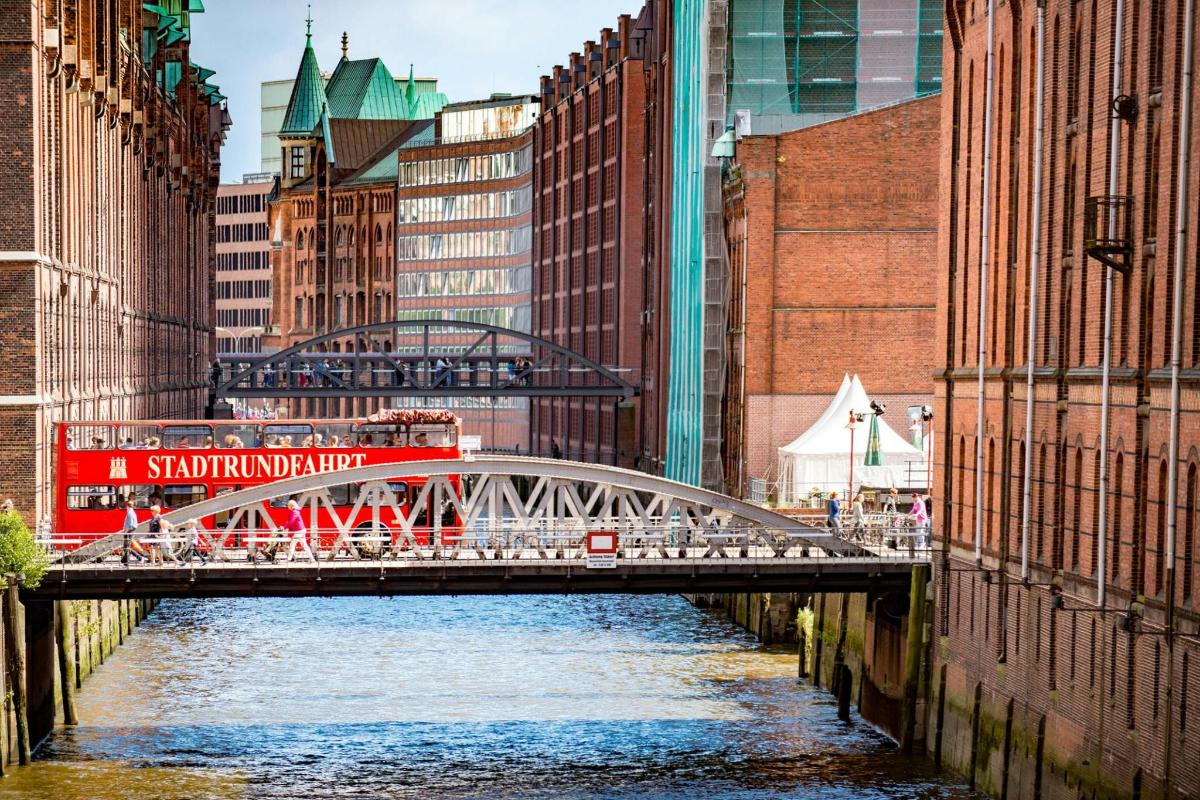 a red train crossing a bridge over a river in a city