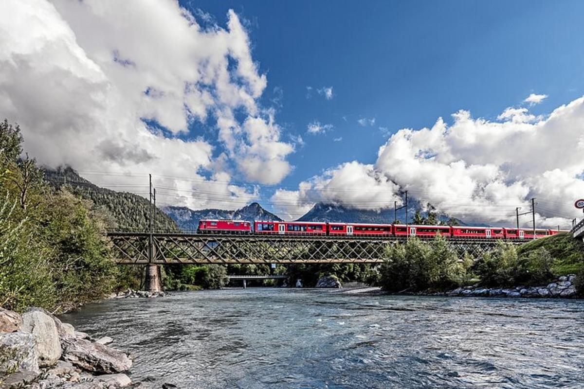 a red train crossing a bridge over a river