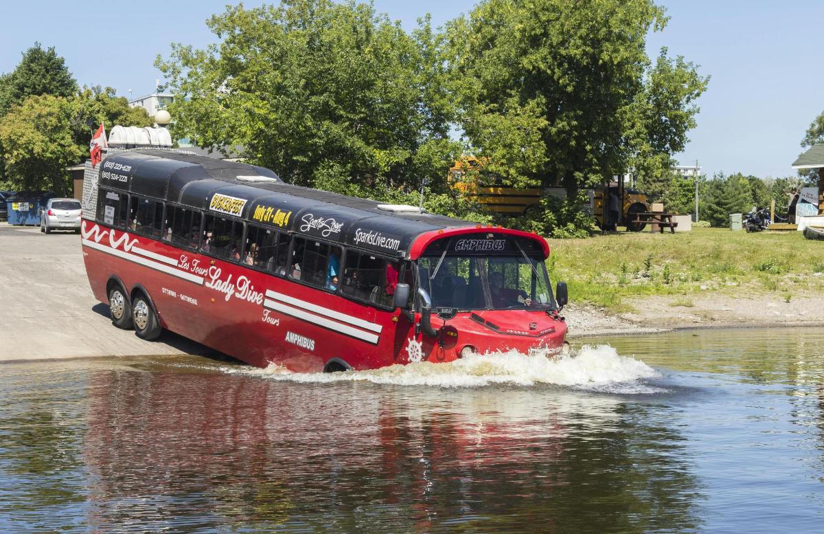 a red bus driving through a river in the water