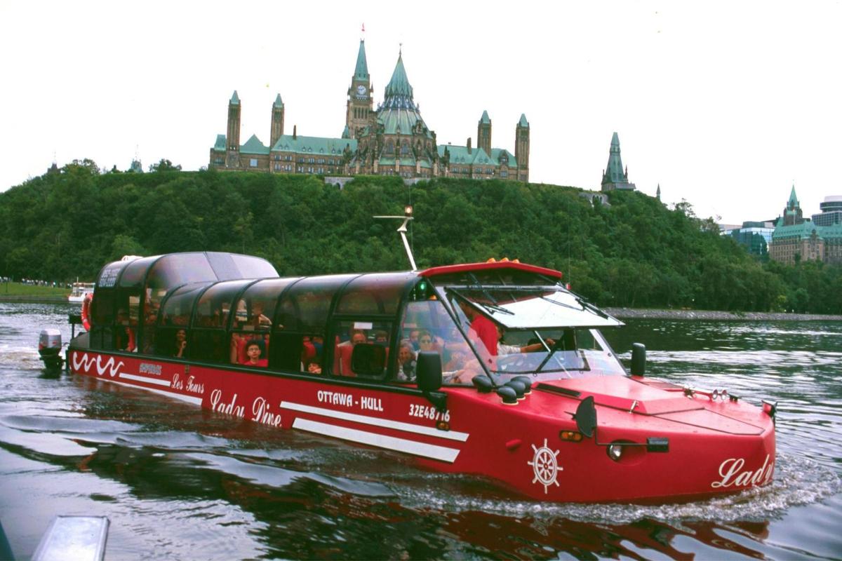 a red boat on the river with a city in the background