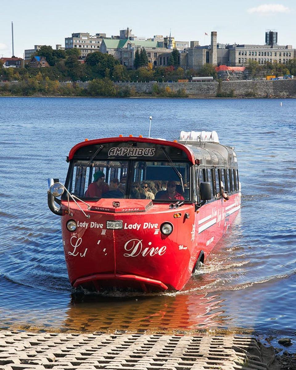 a red bus in the water on a river