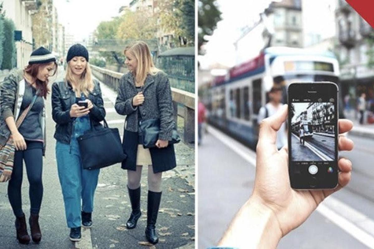 um homem tirando uma foto de duas mulheres caminhando pela rua