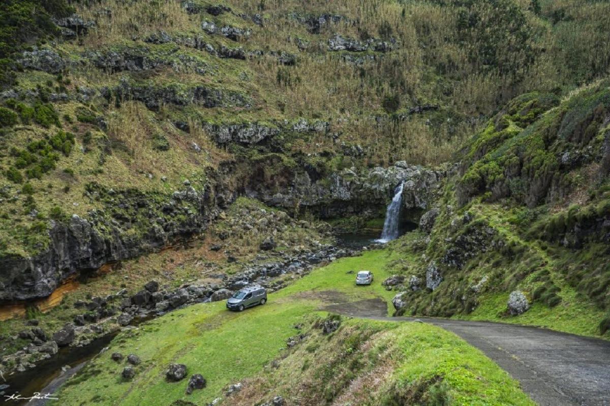 dua buah kereta diletakkan di atas jalan di sebelah air terjun