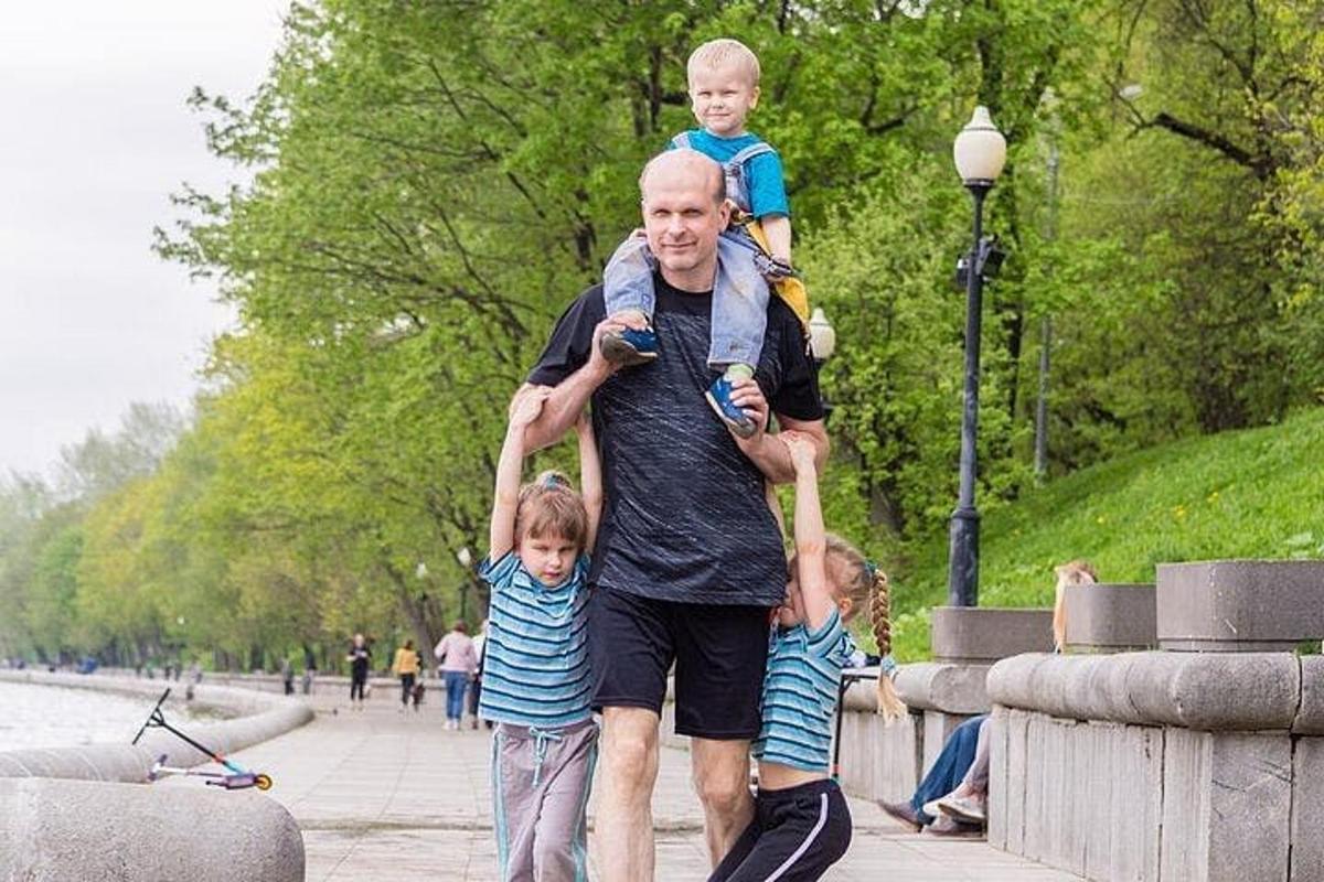 a man carrying two children on his shoulders