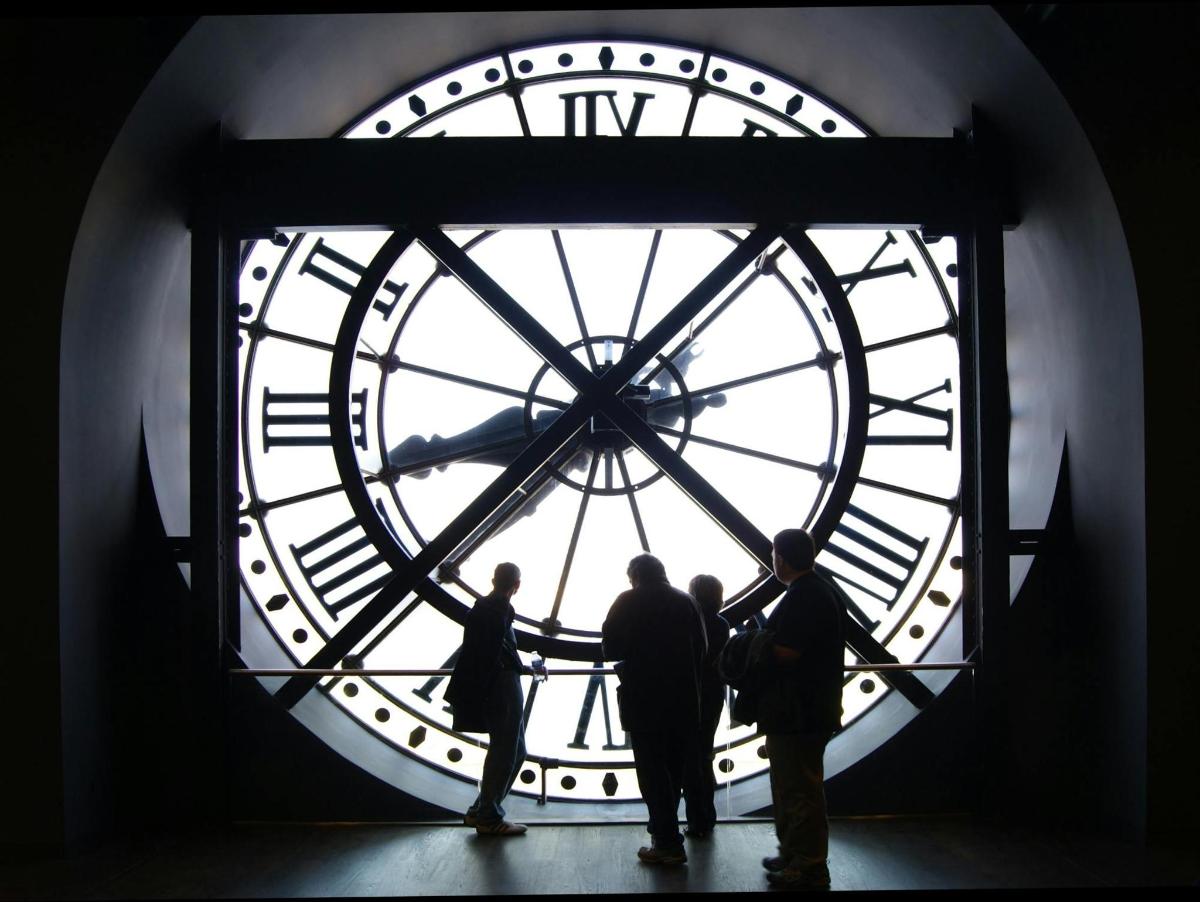 un groupe de personnes debout devant une grande horloge
