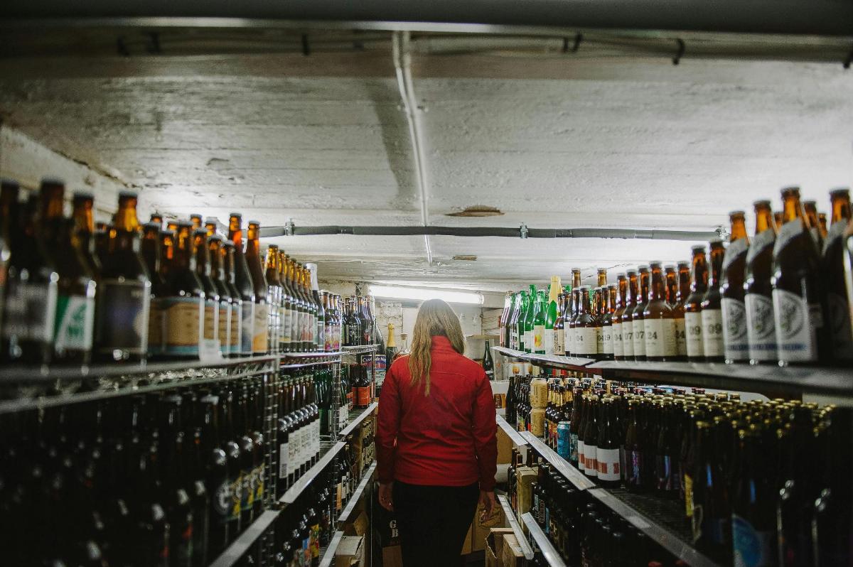 a woman walking through a store filled with bottles of beer