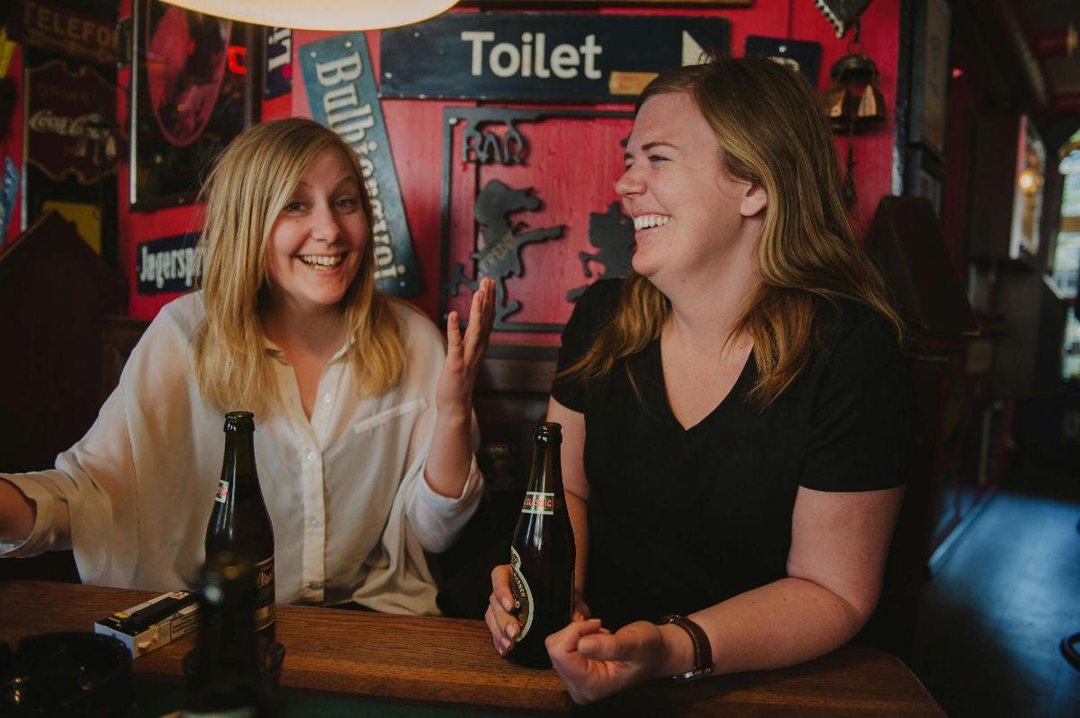 two women sitting at a bar with bottles of wine