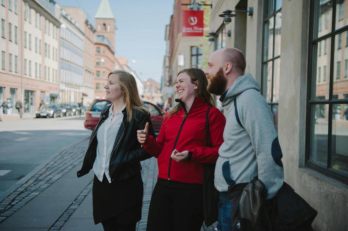 two women and a man standing on a city street