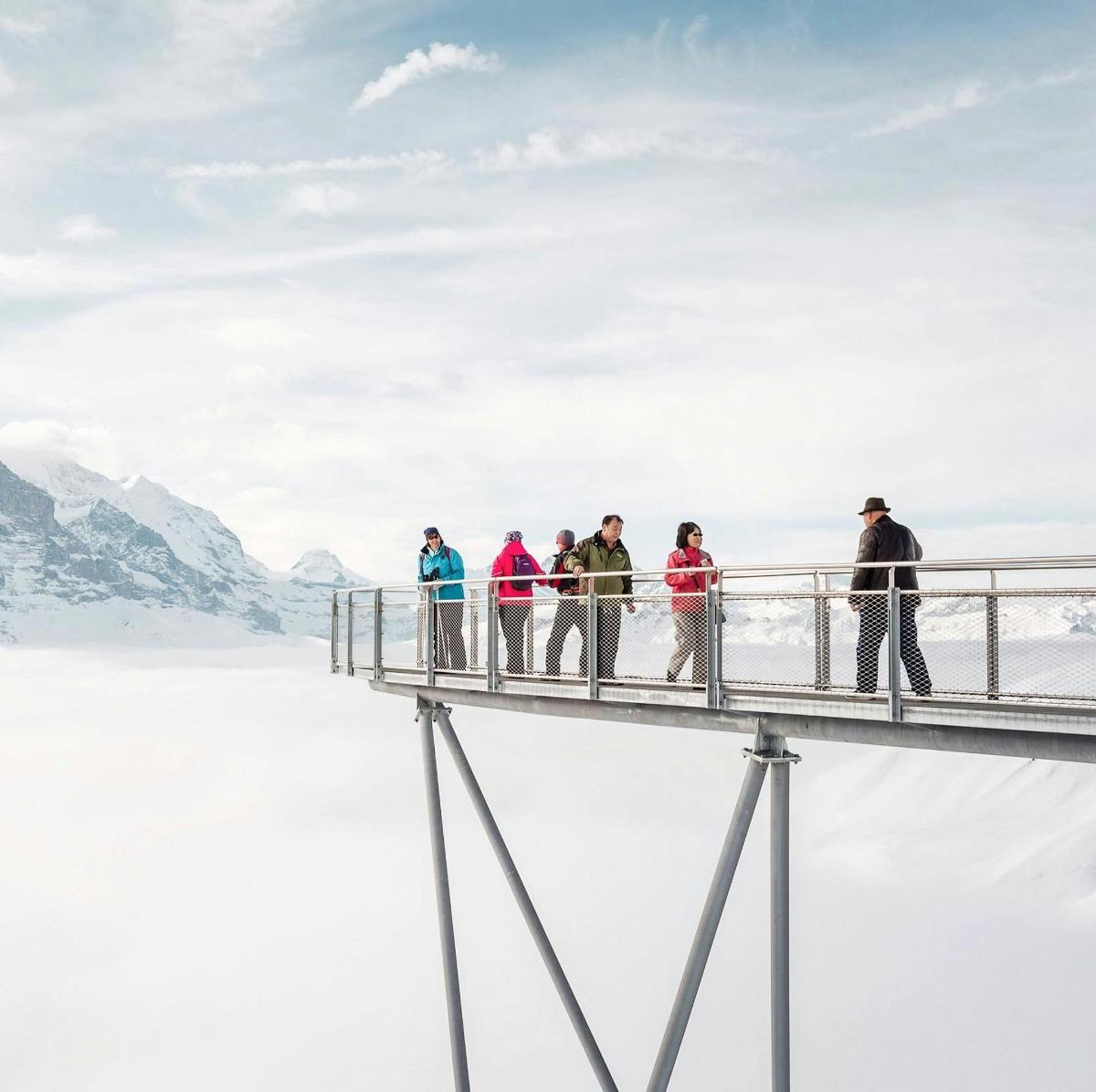 a group of people standing on a bridge in the snow