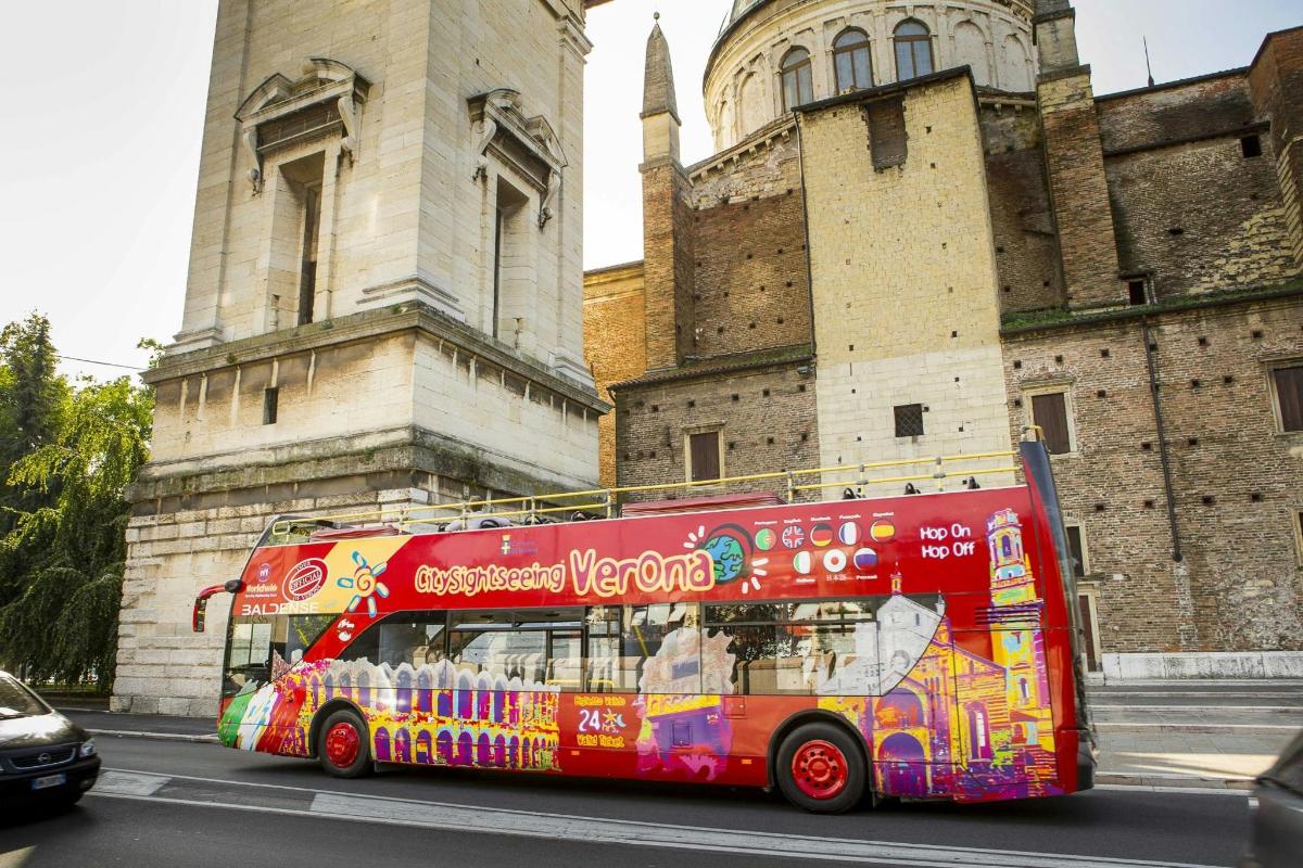 un autobuz roșu cu etaj care trece pe lângă o clădire