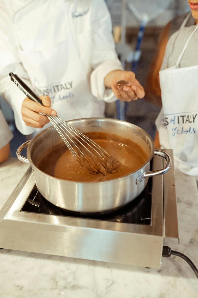 a person stirring a pot with a pair of whiskes