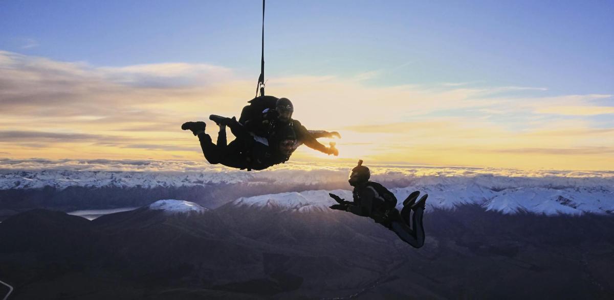 two people are hanging from a rope over a mountain