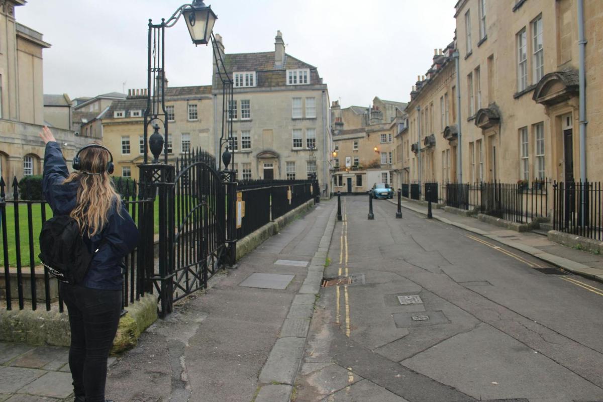 a woman standing next to a fence on a street