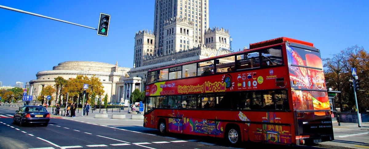 a red double decker bus driving down a city street