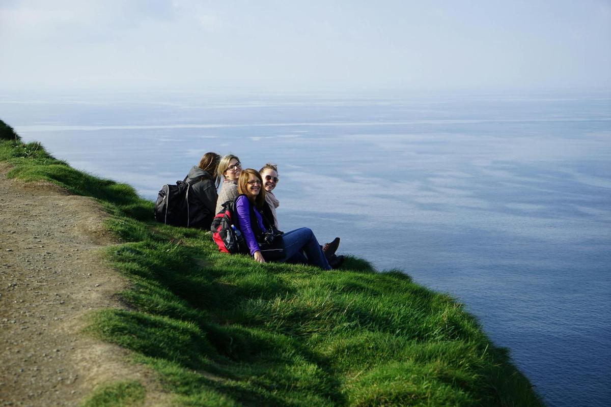 a group of people sitting on a hill overlooking the water