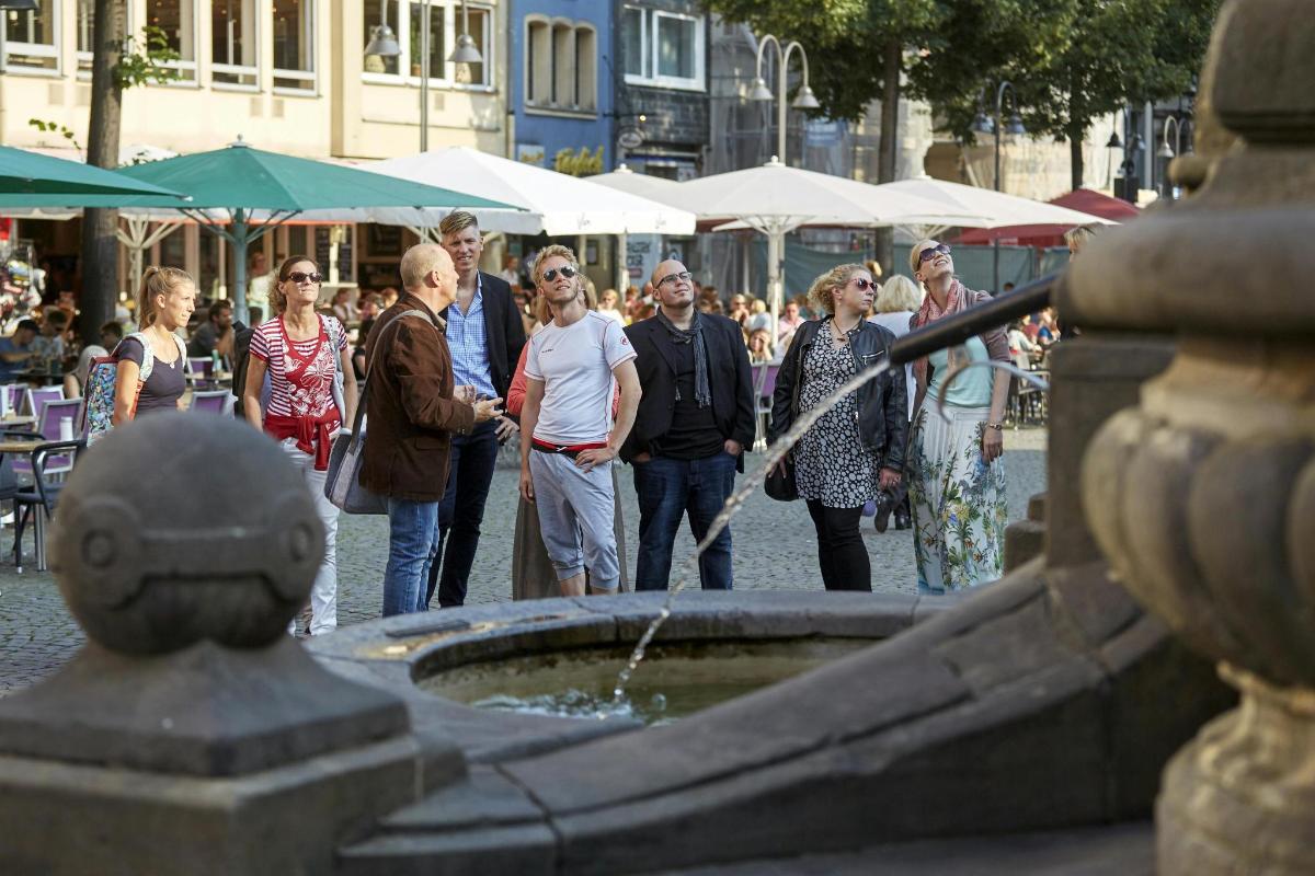 grupė žmonių, stovinčių aplink vandens fontaną