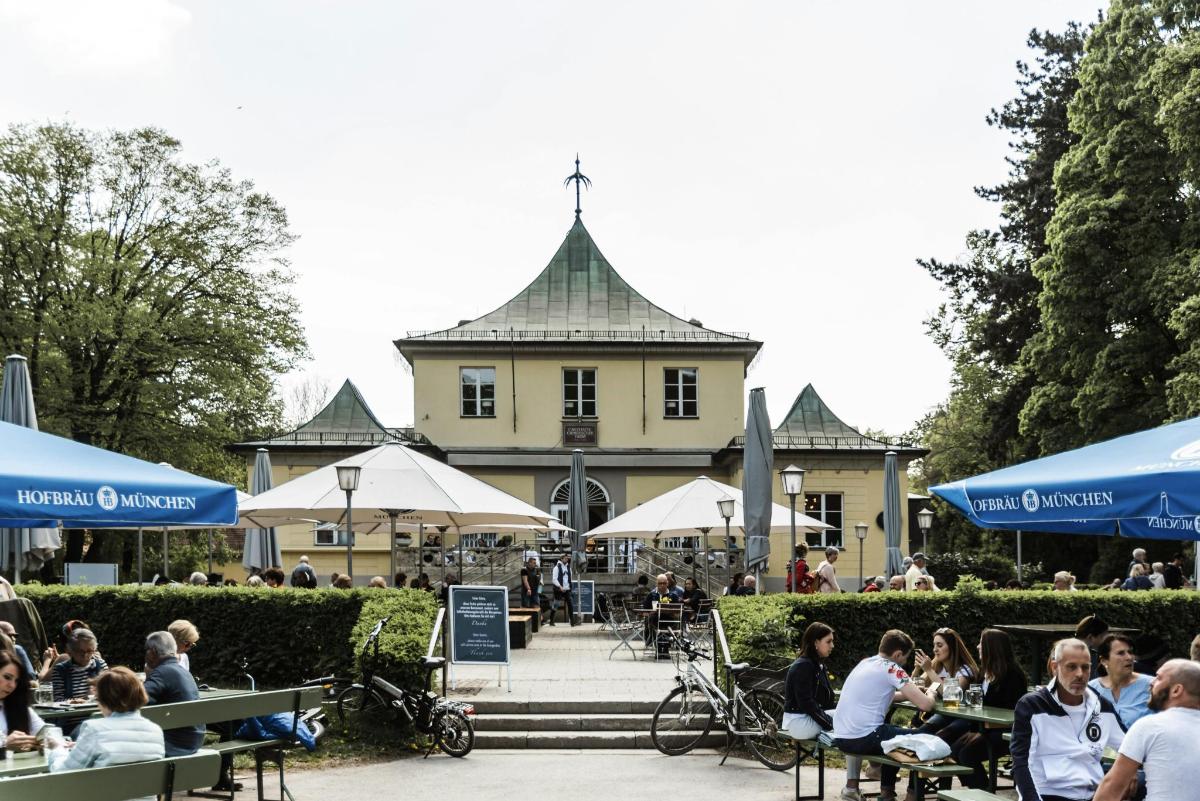 skupina lidí sedících u stolů před budovou
