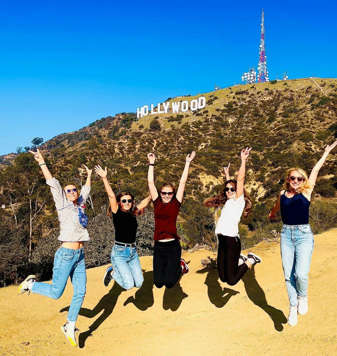 Skupina lidí skáče před hollywoodskou cedulí