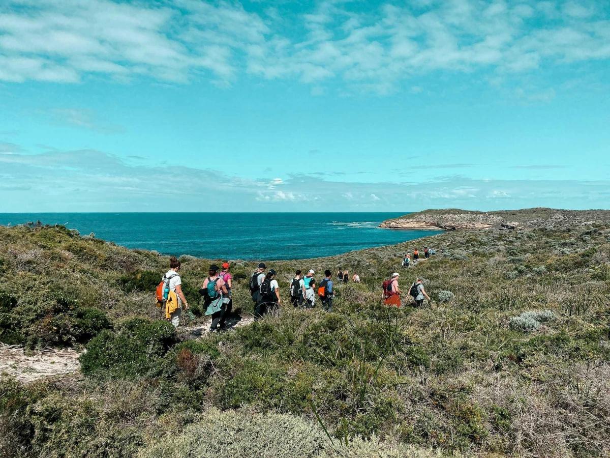 um grupo de pessoas caminhando em uma colina perto do oceano