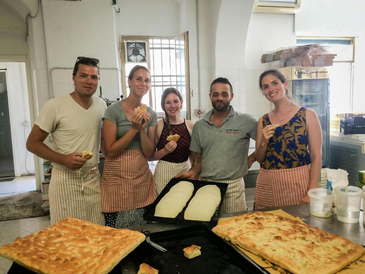 un gruppo di persone in piedi in una cucina con la pizza
