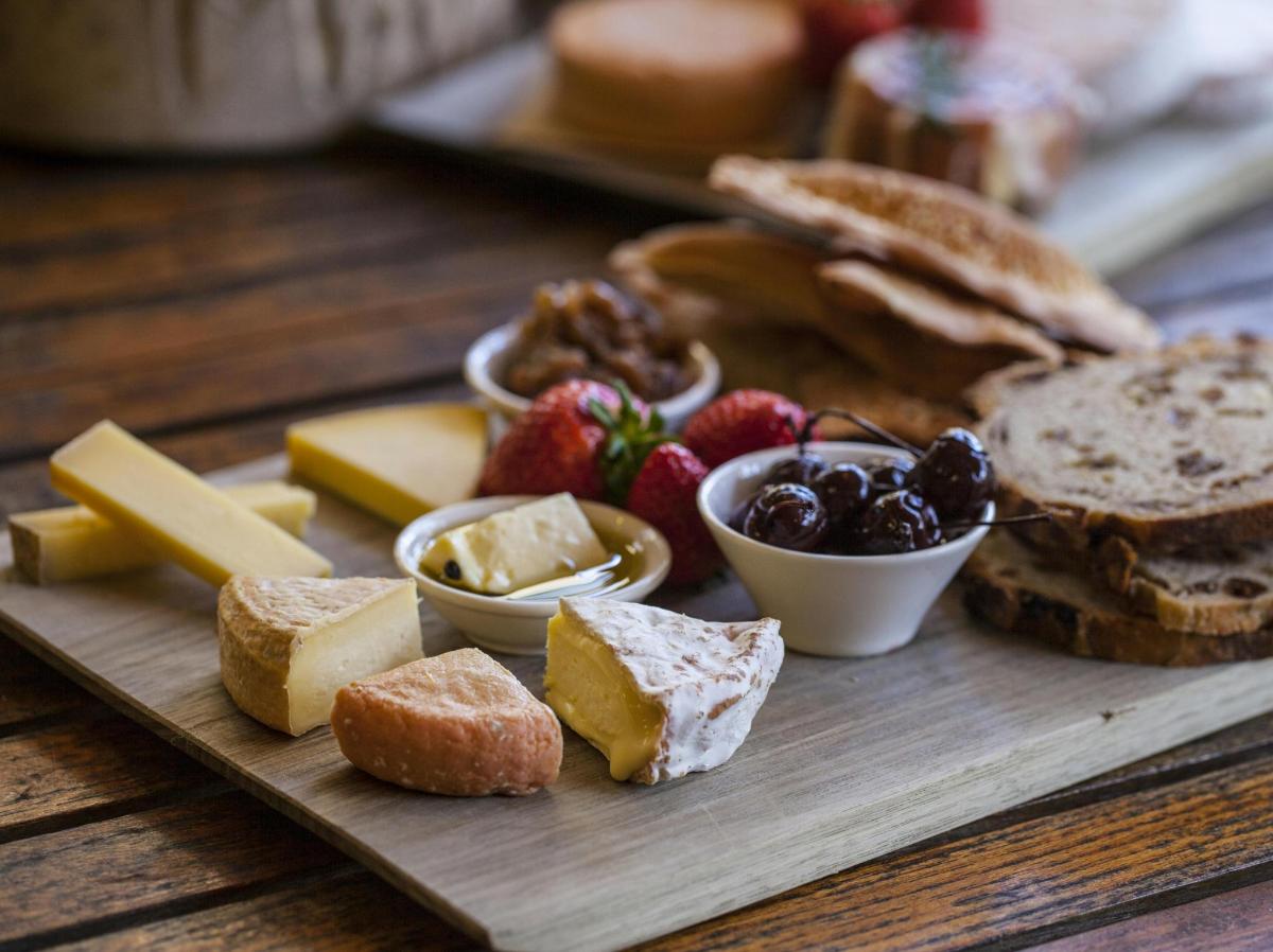 ein Holztablett mit Käse, Brot und Obst