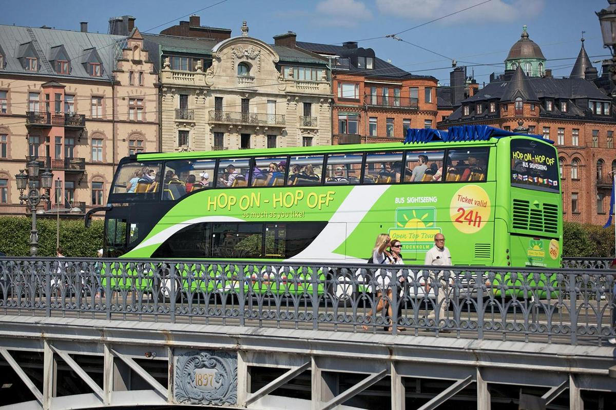 a green double decker bus on a bridge