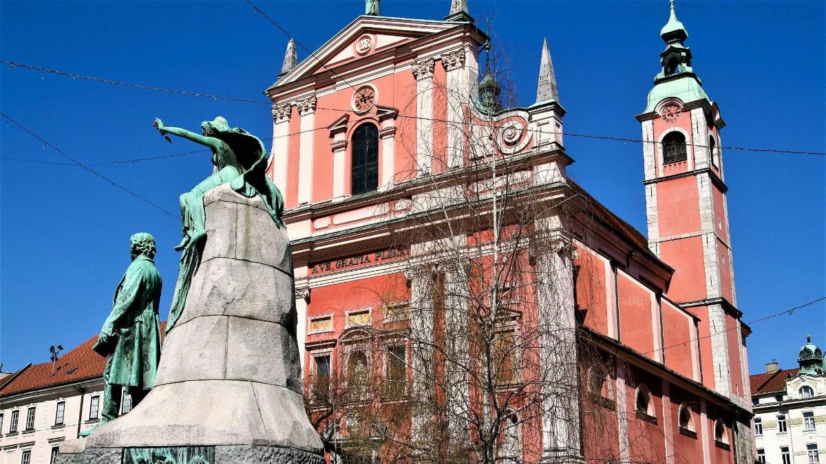 статуя перед будівлею з годинниковою вежею