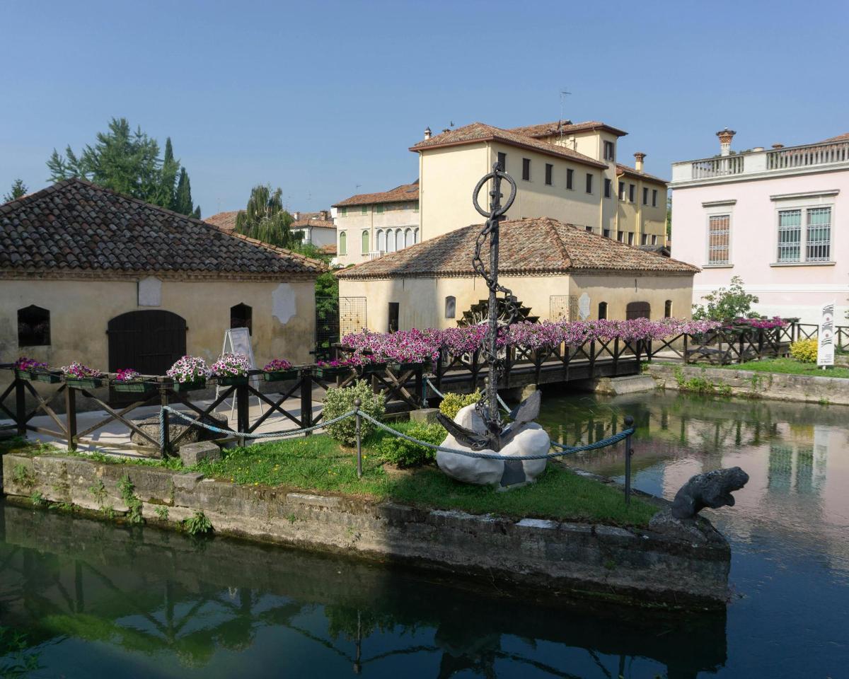 un pont sobre un riu amb dos ànecs a l'aigua