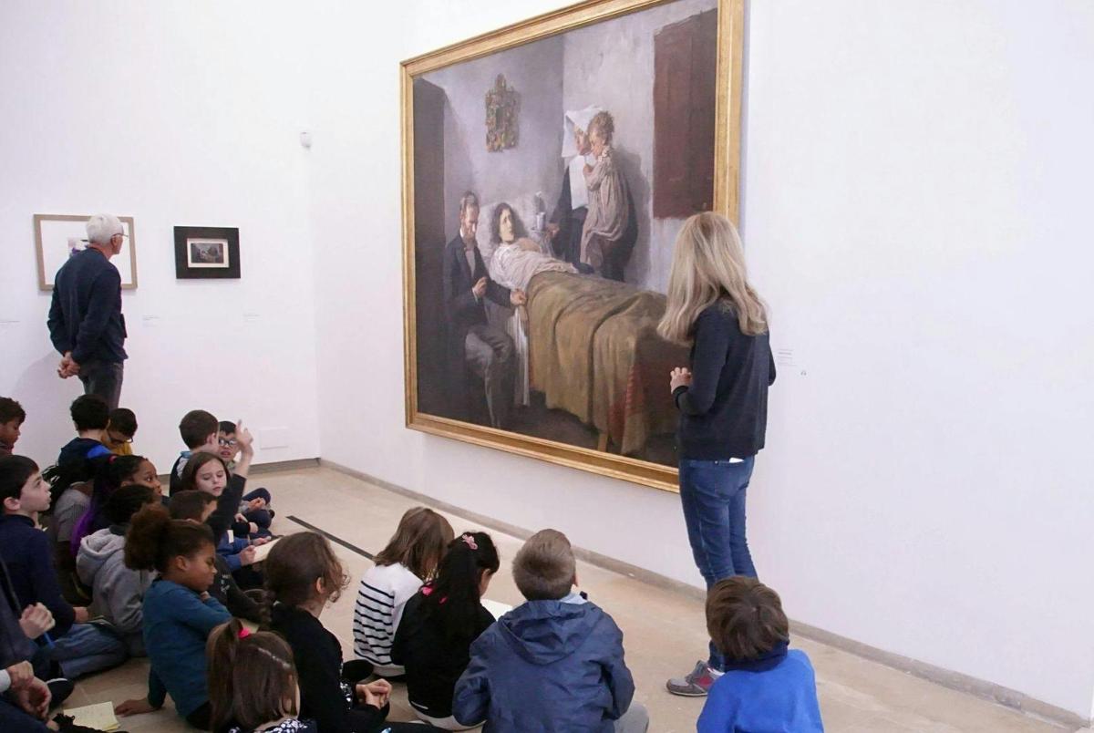 a group of children watching a woman looking at a painting