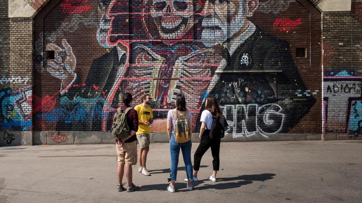 skupina lidí stojících před nástěnnou malbou