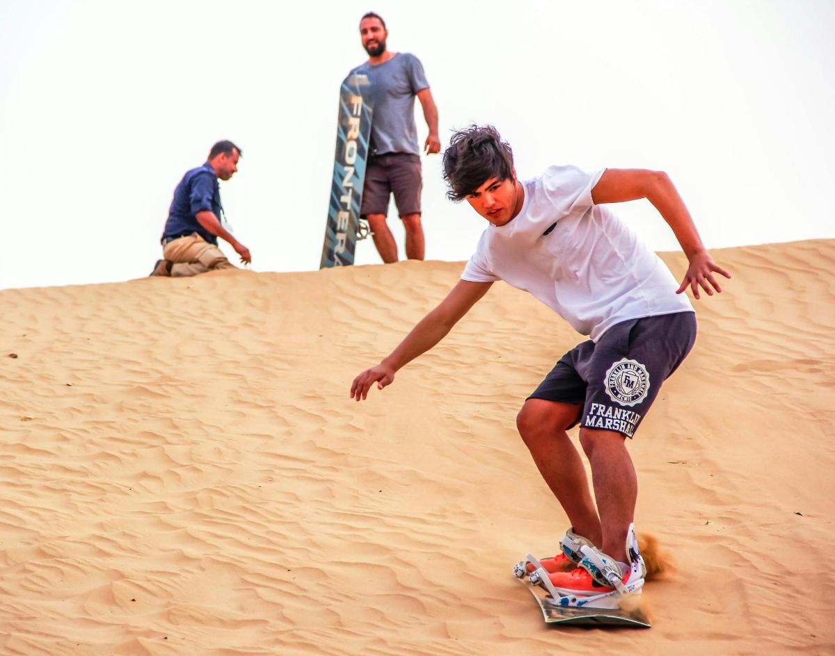 ein Mann, der mit einem Skateboard einen Sandhügel hinunterfährt