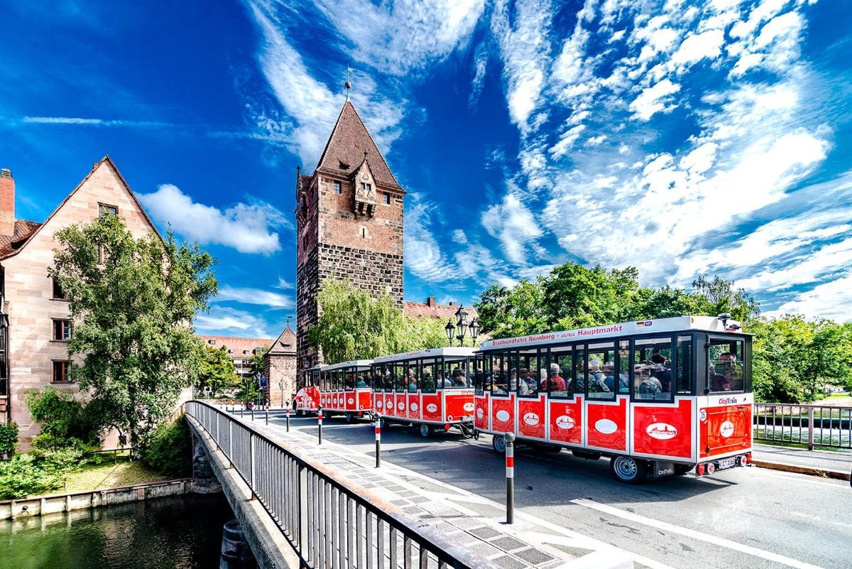 Un tren rojo en un puente frente a un castillo.