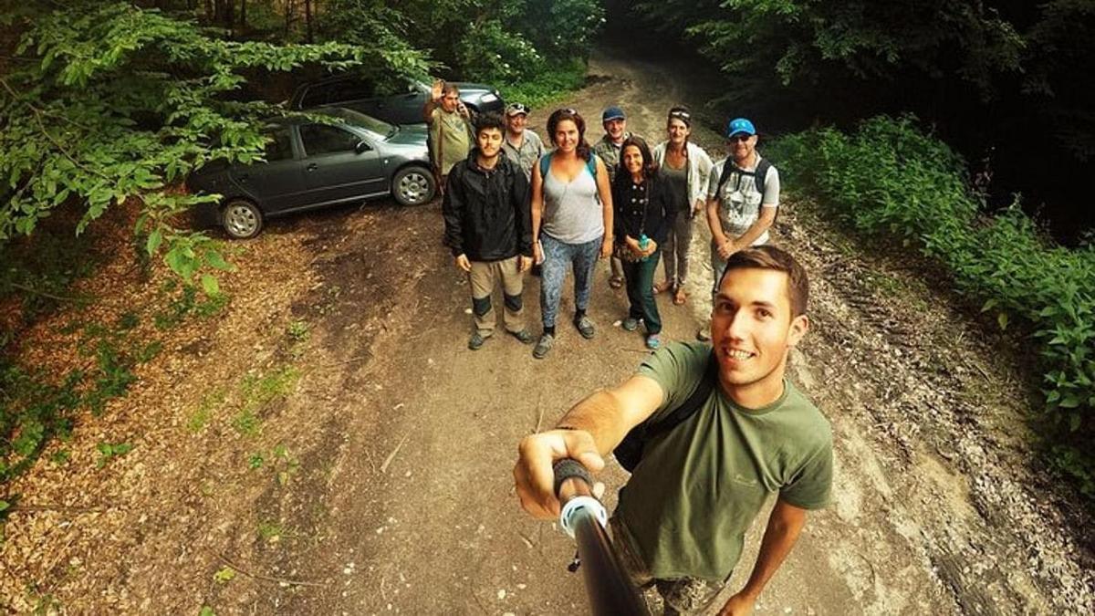 a group of people standing on a dirt road with a man on a bike
