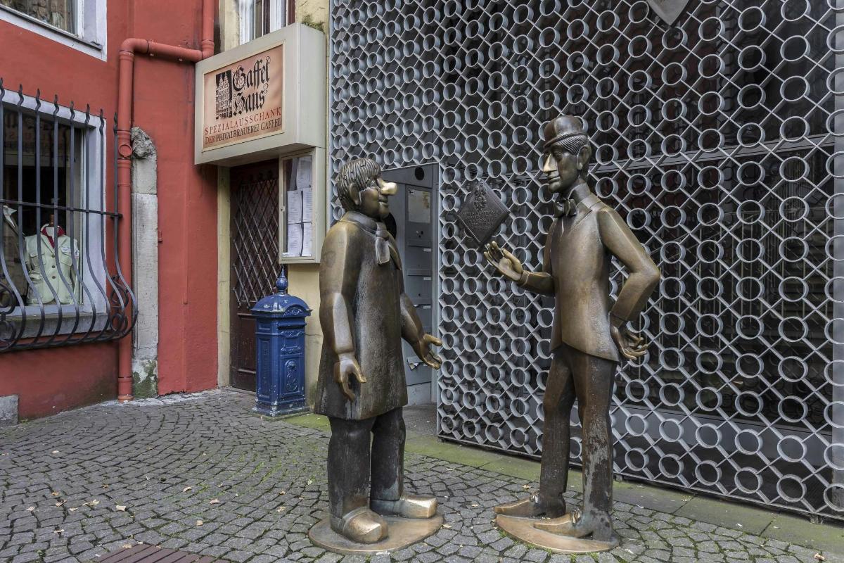 zwei Statuen von Männern, die vor einem Gebäude stehen
