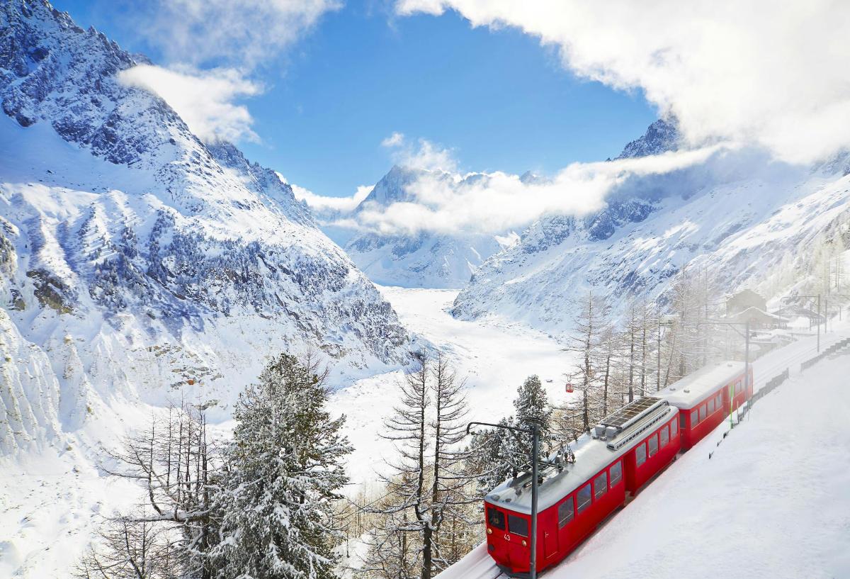 a red train traveling through a snow covered mountain