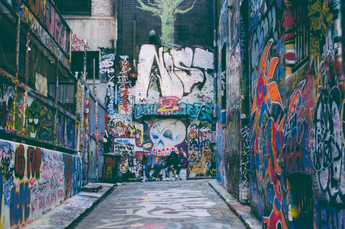 um beco coberto de grafite com uma pessoa caminhando por ele
